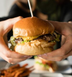 Photo shows someone's hands holding up a large beef burger with cheese. Innocent Meat has raised €6 million in its most recent fundraising round to help develop and scale its cultivated meat system, which it says is much more resource-efficient than traditional meat