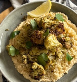 pesto cauliflower bites over grains and hummus served with lemon