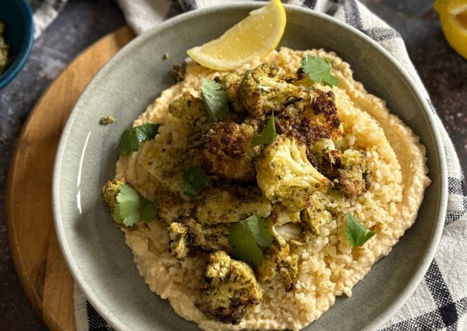 pesto cauliflower bites over grains and hummus served with lemon