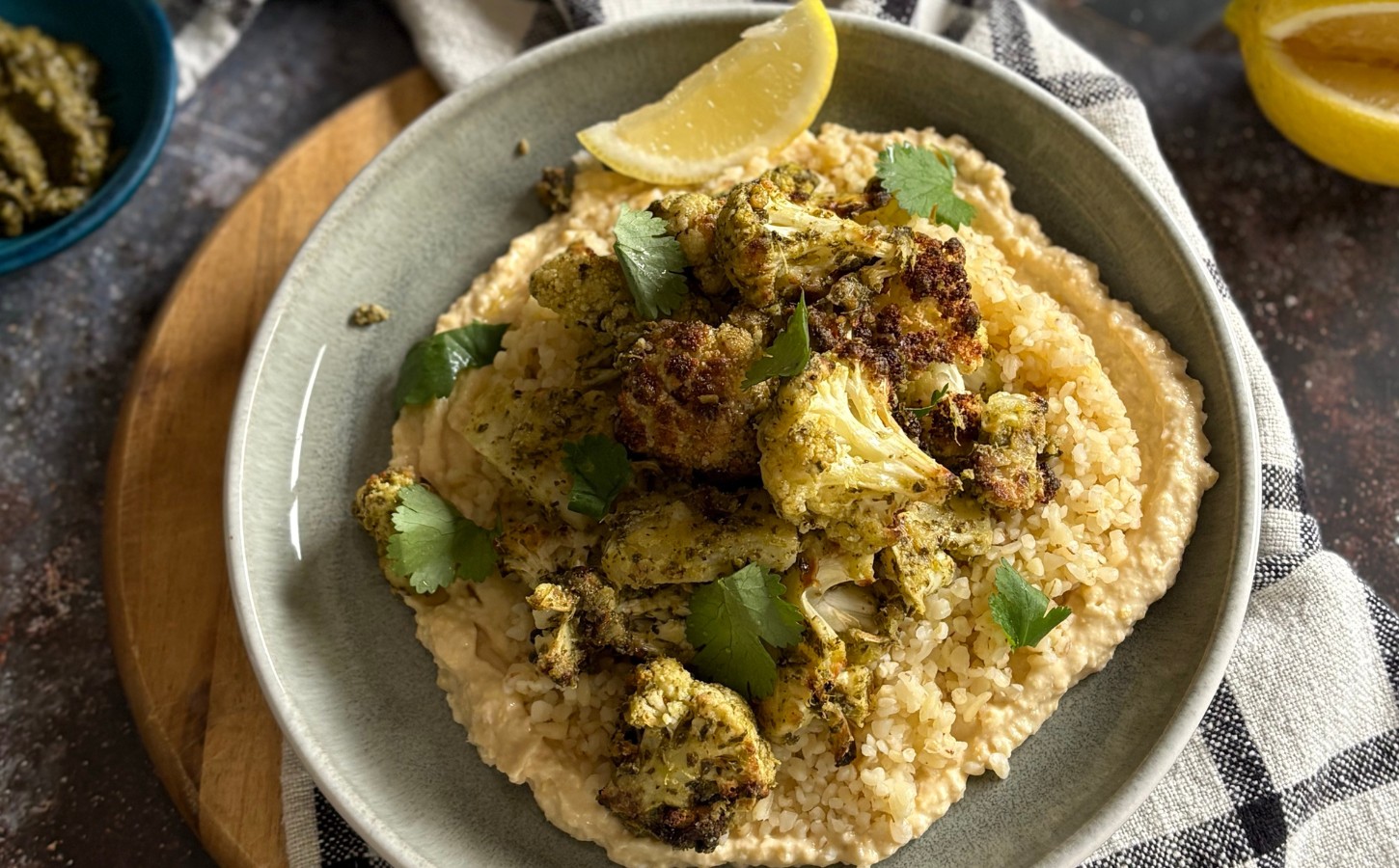 pesto cauliflower bites over grains and hummus served with lemon