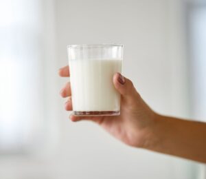 Photo shows someone's hand holding up a glass of milk. Nine people are currently experiencing “serious illness” in Idaho after drinking raw dairy milk, and two children have been hospitalized