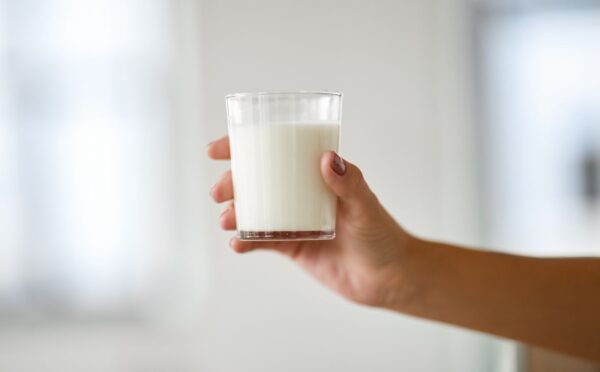 Photo shows someone's hand holding up a glass of milk. Nine people are currently experiencing “serious illness” in Idaho after drinking raw dairy milk, and two children have been hospitalized