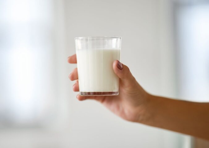 Photo shows someone's hand holding up a glass of milk. Nine people are currently experiencing “serious illness” in Idaho after drinking raw dairy milk, and two children have been hospitalized