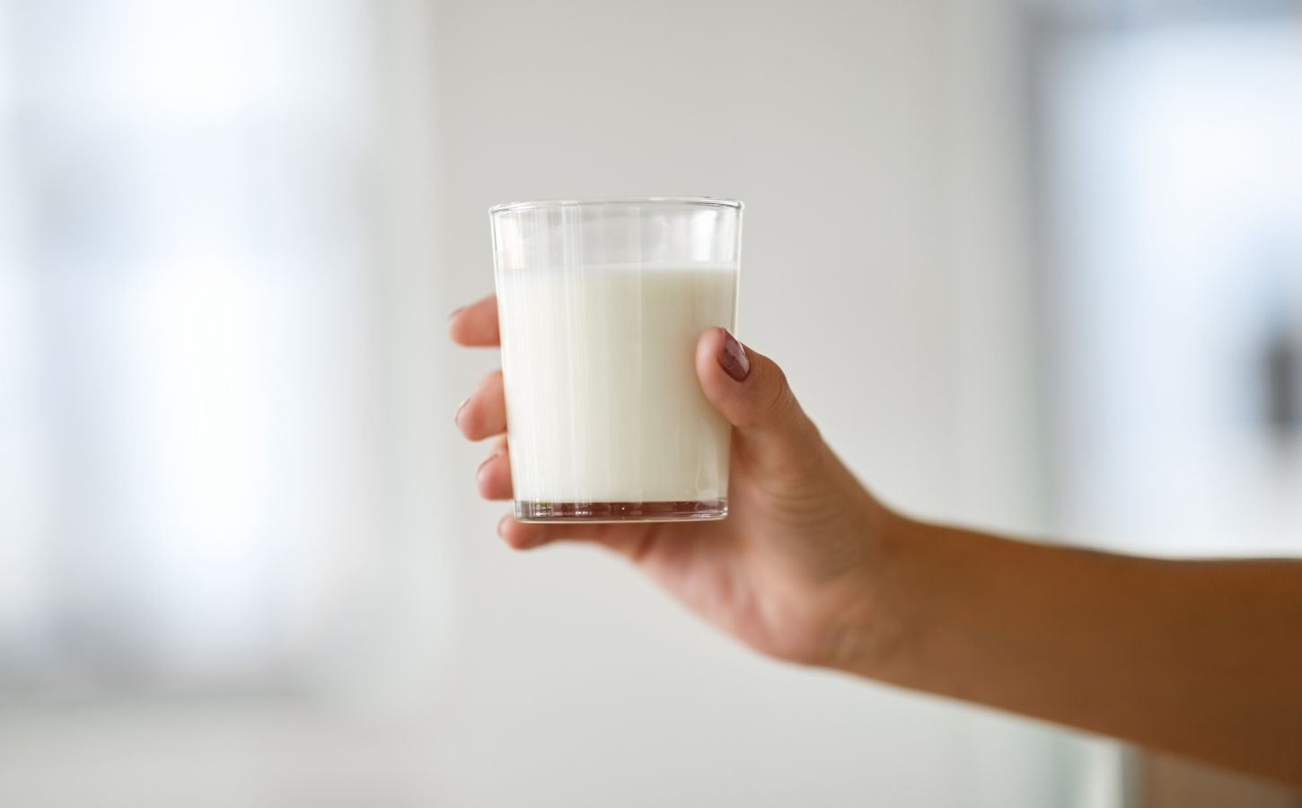 Photo shows someone's hand holding up a glass of milk. Nine people are currently experiencing “serious illness” in Idaho after drinking raw dairy milk, and two children have been hospitalized