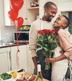 Photo shows a young couple embracing in the kitchen while cooking dinner, holding flowers, with red heart-shaped balloons in the background. Ahead of Valentine's Day, research by Redefine Meat found that nearly half of UK vegans saw dietary incompatibility as a relationship and dating dealbreaker