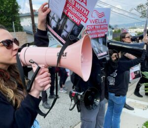 Photo shows CAFT activists demonstrating, including one person holding a bullhorn and another holding a placard. Wella announced that it will no longer sponsor Milan Fashion Week following recent protests and public pressure over fur.