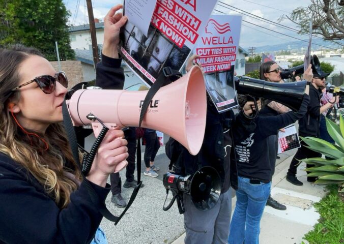 Photo shows CAFT activists demonstrating, including one person holding a bullhorn and another holding a placard. Wella announced that it will no longer sponsor Milan Fashion Week following recent protests and public pressure over fur.