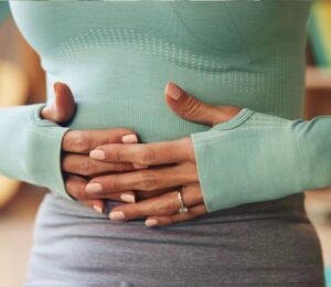 Woman holding her stomach, illustrating digestive discomfort and article exploring research on the link between vitamin B1 and IBS