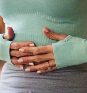 Woman holding her stomach, illustrating digestive discomfort and article exploring research on the link between vitamin B1 and IBS