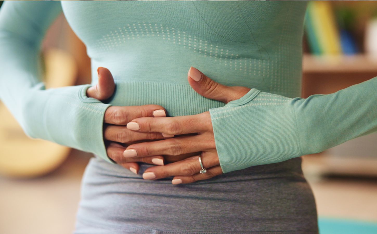 Woman holding her stomach, illustrating digestive discomfort and article exploring research on the link between vitamin B1 and IBS