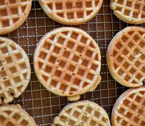 Freshly made oat waffles cooling on a wire rack as part of freezer friendly vegan meals prep