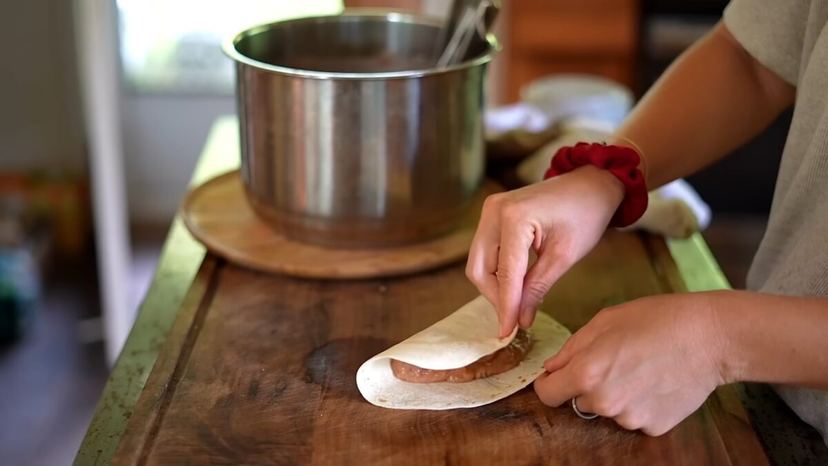 Howlett folds a tortilla filled with refried beans to prepare quesadillas, one of her freezer friendly vegan meals