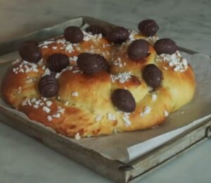 A golden braided vegan Easter brioche topped with chocolate Easter eggs, fresh from the oven