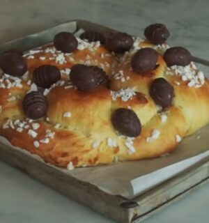 A golden braided vegan Easter brioche topped with chocolate Easter eggs, fresh from the oven