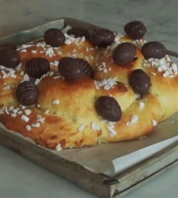 A golden braided vegan Easter brioche topped with chocolate Easter eggs, fresh from the oven