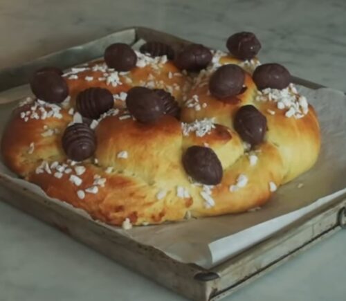 A golden braided vegan Easter brioche topped with chocolate Easter eggs, fresh from the oven