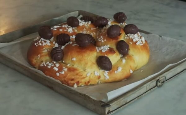A golden braided vegan Easter brioche topped with chocolate Easter eggs, fresh from the oven