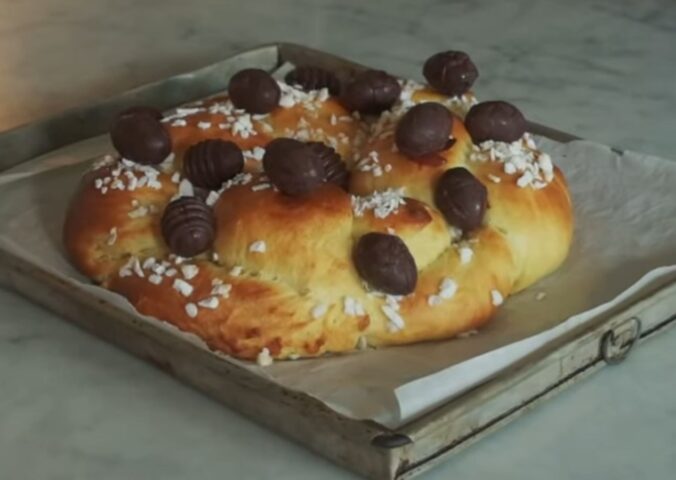 A golden braided vegan Easter brioche topped with chocolate Easter eggs, fresh from the oven