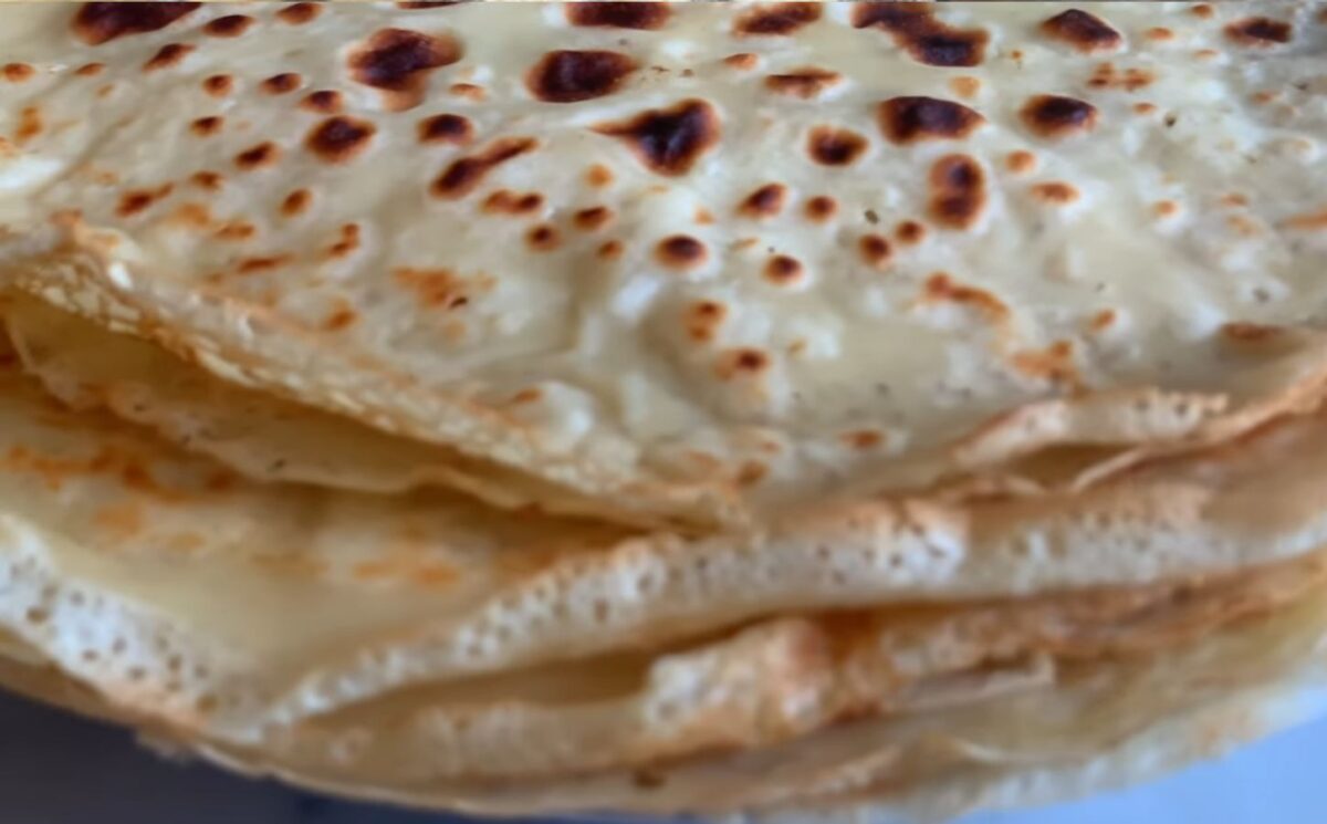 A stack of freshly cooked vegan orange zest crepes, showing their thin, golden texture