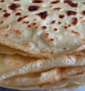 A stack of freshly cooked vegan orange zest crepes, showing their thin, golden texture
