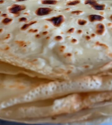 A stack of freshly cooked vegan orange zest crepes, showing their thin, golden texture