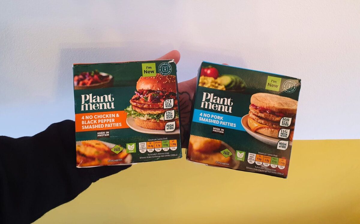 Photo shows a person's hand as they hold up the two "smashed" burger products from Aldi, the No Pork Smashed Patties and the No Chicken & Black Pepper Smashed Patties.