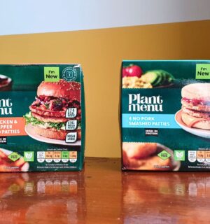 Photo shows the two "smashed" burger products from Aldi - the No Pork Smashed Patties and the No Chicken & Black Pepper Smashed Patties - on a wooden dining table against a yellow and white background