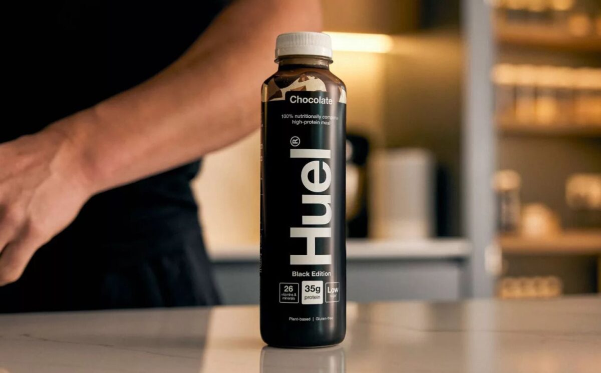 Photo shows someone's arm as they stand behind a bottle of Huel on a kitchen worktop. Danone SA has agreed to buy Huel, a leading plant-based protein brand based in the UK, for €1 billion