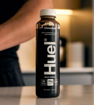 Photo shows someone's arm as they stand behind a bottle of Huel on a kitchen worktop. Danone SA has agreed to buy Huel, a leading plant-based protein brand based in the UK, for €1 billion