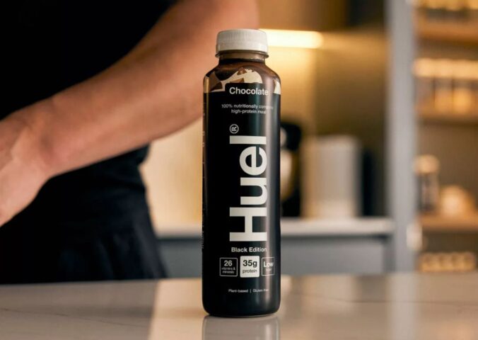 Photo shows someone's arm as they stand behind a bottle of Huel on a kitchen worktop. Danone SA has agreed to buy Huel, a leading plant-based protein brand based in the UK, for €1 billion