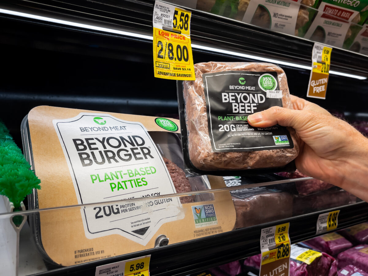 Photo shows someone taking a single packet of Beyond Meat's mince from a refrigerator of vegetarian burgers and sausages