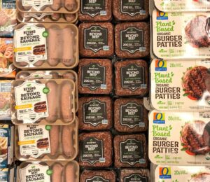 Photo shows a large refrigerator full of plant-based burgers, sausages, and other meat-alternatives, including several products made by Beyond Meat