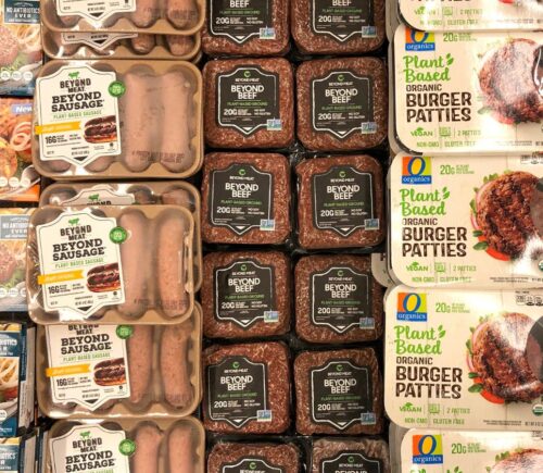 Photo shows a large refrigerator full of plant-based burgers, sausages, and other meat-alternatives, including several products made by Beyond Meat