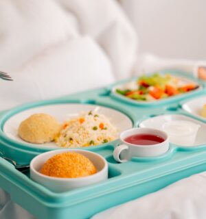 Photo shows someone eating a healthy, plant-based hospital meal in bed. A catering company has reduced hospital food emissions by 22 percent over the last year with “Greener By Default” plant-based meals