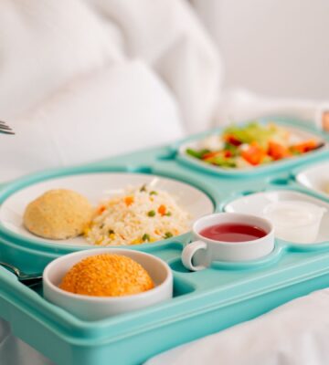 Photo shows someone eating a healthy, plant-based hospital meal in bed. A catering company has reduced hospital food emissions by 22 percent over the last year with “Greener By Default” plant-based meals