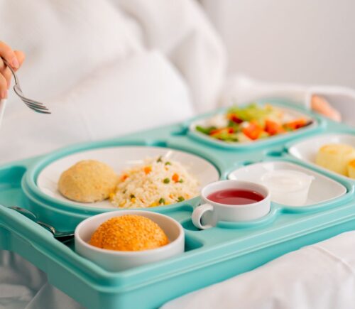 Photo shows someone eating a healthy, plant-based hospital meal in bed. A catering company has reduced hospital food emissions by 22 percent over the last year with “Greener By Default” plant-based meals