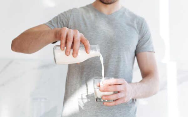 Photo shows a man pouring a glass of milk from a bottle. A new AHDB report claims that dairy is beneficial for both human health and the environment, but food advocacy NGO ProVeg described the findings as "another exercise in marketing over health and evidence"