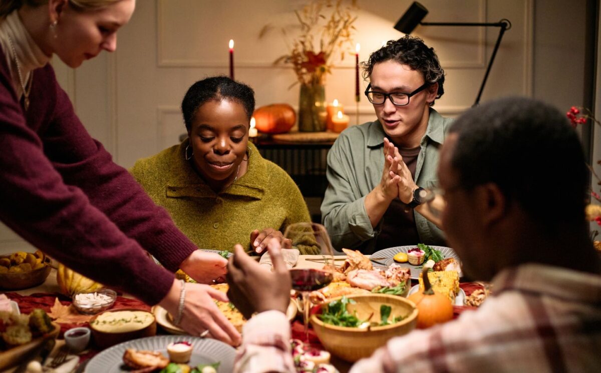 Photo shows a group of friends sitting down to a meal together. Vegans use several different types of social skills to adapt and “survive” difficulties in a predominantly meat-eating world
