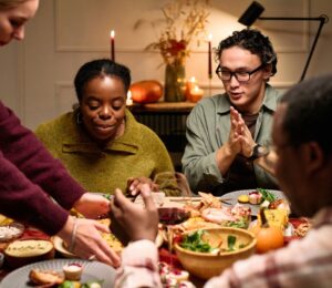 Photo shows a group of friends sitting down to a meal together. Vegans use several different types of social skills to adapt and “survive” difficulties in a predominantly meat-eating world