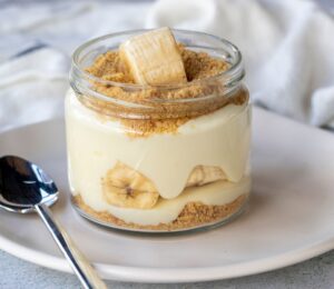 Photo shows a single serve banana pudding in a glass jar. Banana pudding is not traditionally vegan-friendly, but it can be easily made vegan with the use of common plant-based ingredients like coconut cream and oat milk