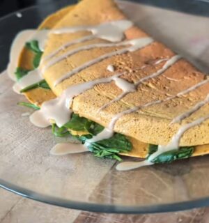 Chickpea omelette drizzled with tahini on a plate, one of Daynesh's quick vegan breakfasts.