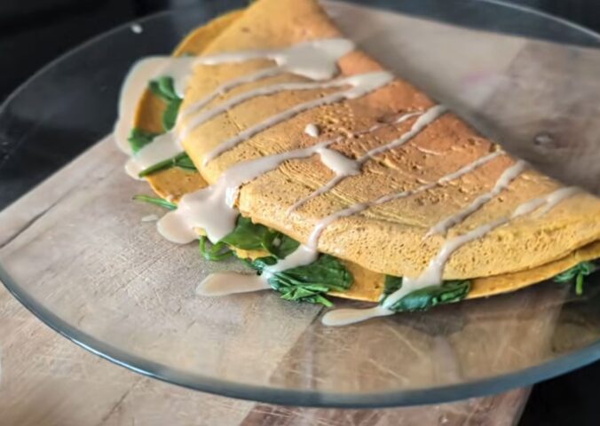 Chickpea omelette drizzled with tahini on a plate, one of Daynesh's quick vegan breakfasts.