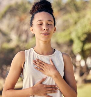 Woman practicing yogic breathing outdoors to illustrate article on how to protect your gut.