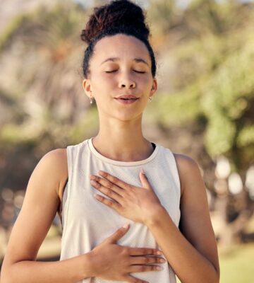 Woman practicing yogic breathing outdoors to illustrate article on how to protect your gut.