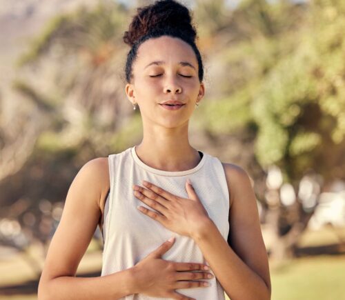 Woman practicing yogic breathing outdoors to illustrate article on how to protect your gut.