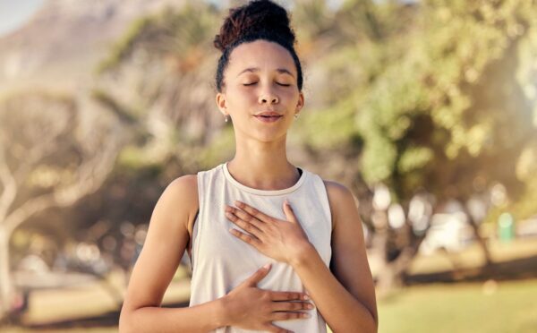 Woman practicing yogic breathing outdoors to illustrate article on how to protect your gut.