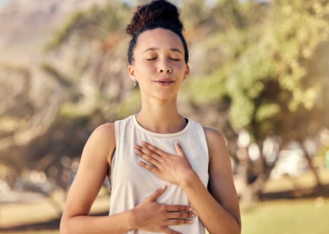 Woman practicing yogic breathing outdoors to illustrate article on how to protect your gut.