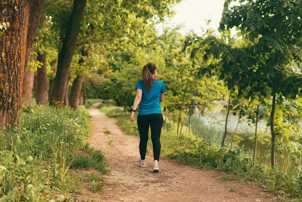 A woman walks along a path in a forest to illustrate an article on how to protect your gut