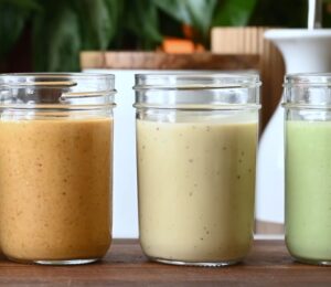 Several jars of Nisha Vora's homemade salad dressings lined up on a cutting board.