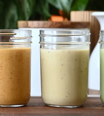 Several jars of Nisha Vora's homemade salad dressings lined up on a cutting board.
